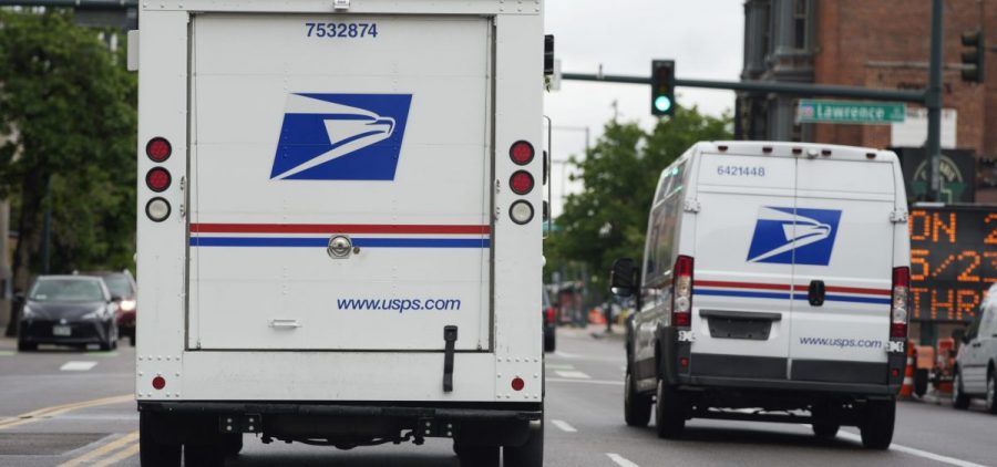 A USPS logo adorns the back doors of United States Postal Service delivery vehicles as they proceed westbound along 20th Street from Stout Street and the main post office in downtown Denver, Wednesday, June 1, 2022.