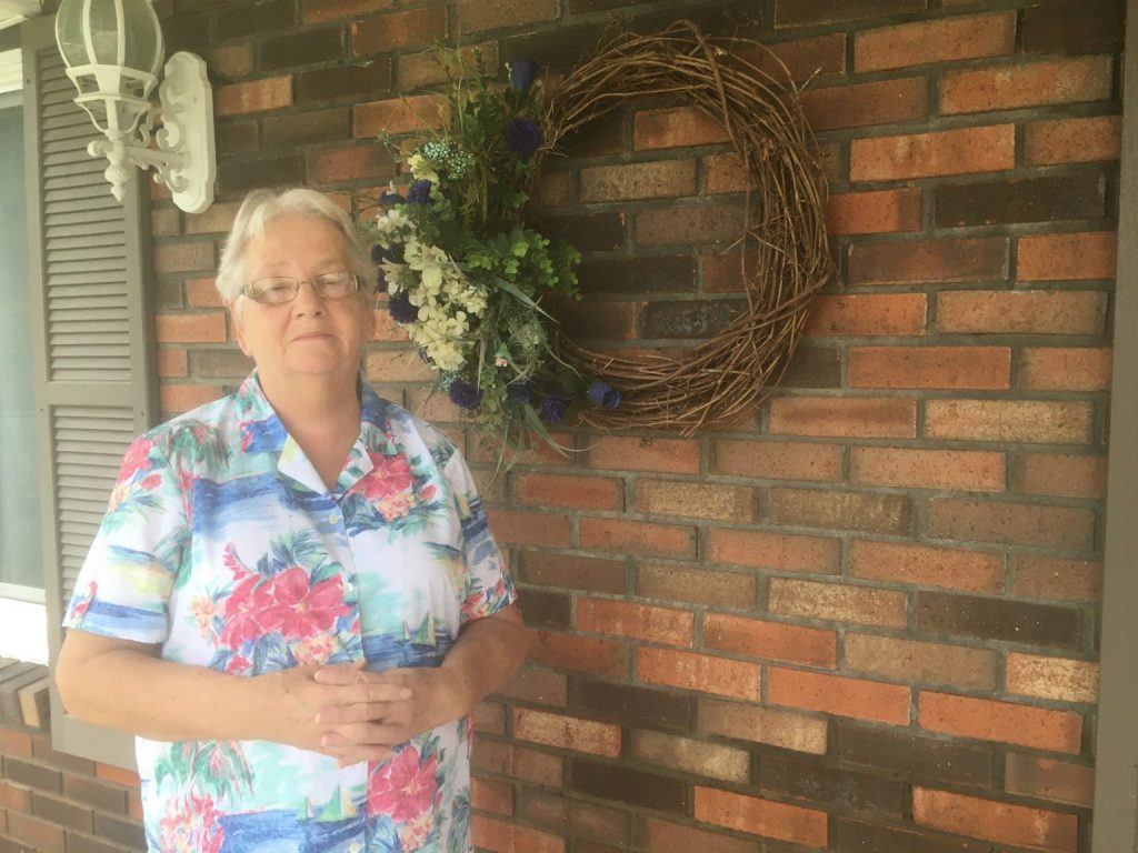 Faye Weaver stands outside of her brick home