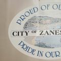 An image of a logo on a trailer during the 2022 Y-Bridge Festival in Zanesville. The logo reads: Proud of our past, City of Zanesville, pride in our future. There is an illustration of the Muskingum River in the center of the logo.