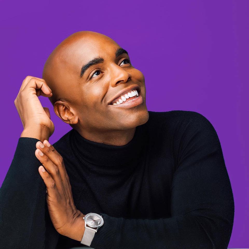 A promotional headshot for Chris Witherspoon, featuring Chris in a black shirt against a purple background.