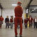 teacher in warehouse with students facing him in semi-circle