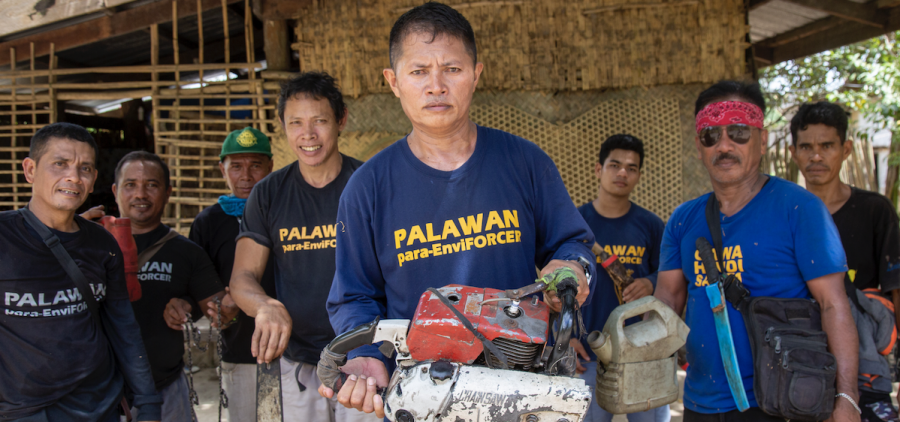group of Phillipino men facing camera holding confiscated chain saws