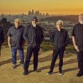 The band Los Lobos on hilltop with major city in the background