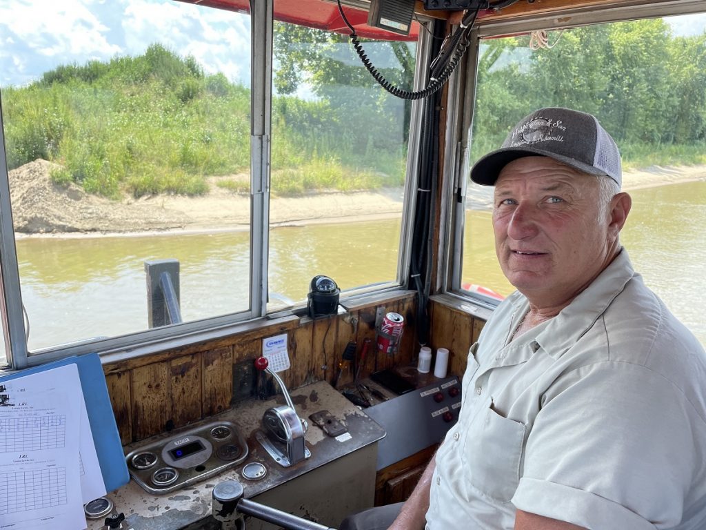 Rick Turner looks at the camera while sitting in the captain chair of his ferry boat on the Ohio River