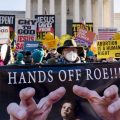 Stephen Parlato of Boulder, Colo., holds a sign that reads "Hands Off Roe!!!" as abortion rights advocates and anti-abortion protesters demonstrate in front of the U.S. Supreme Court, Wednesday, Dec. 1, 2021, in Washington.