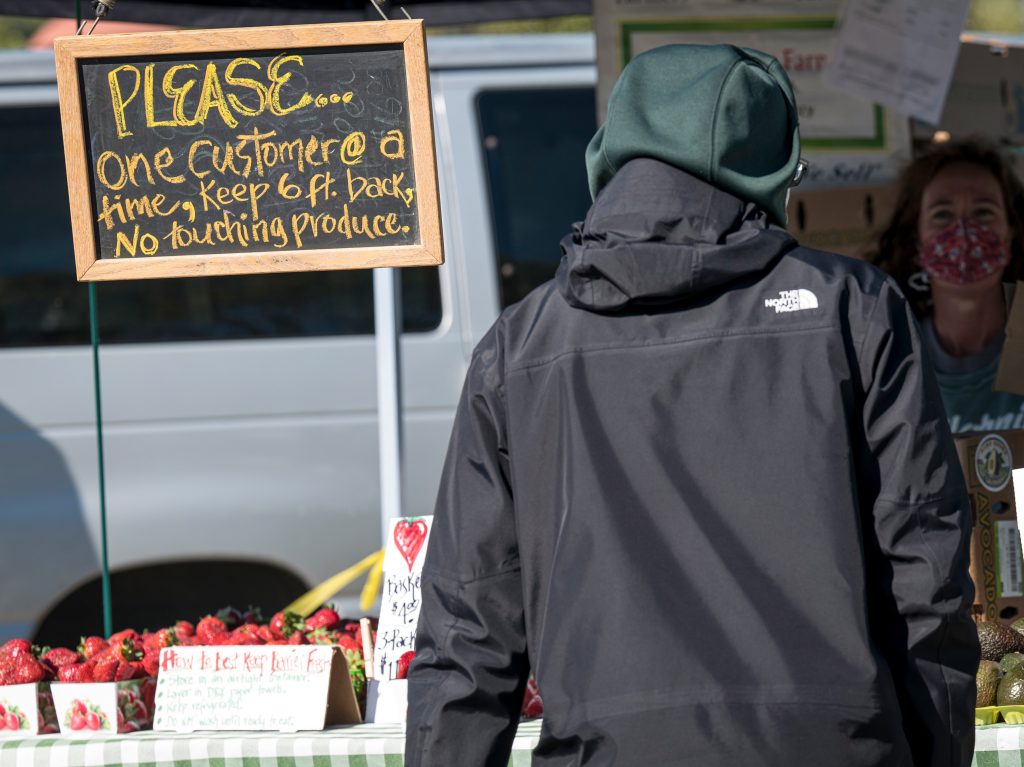 A sign tells shoppers to stand 6 feet back and not to touch the produce at a farmers market in San Rafael, Calif., in March 2020.