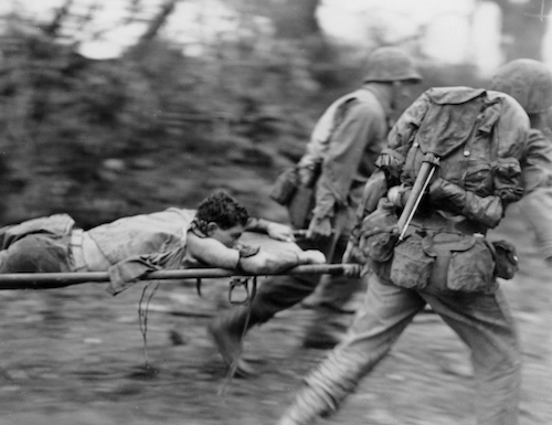 WWII military carry someone on streacher in Okinawa, 1945