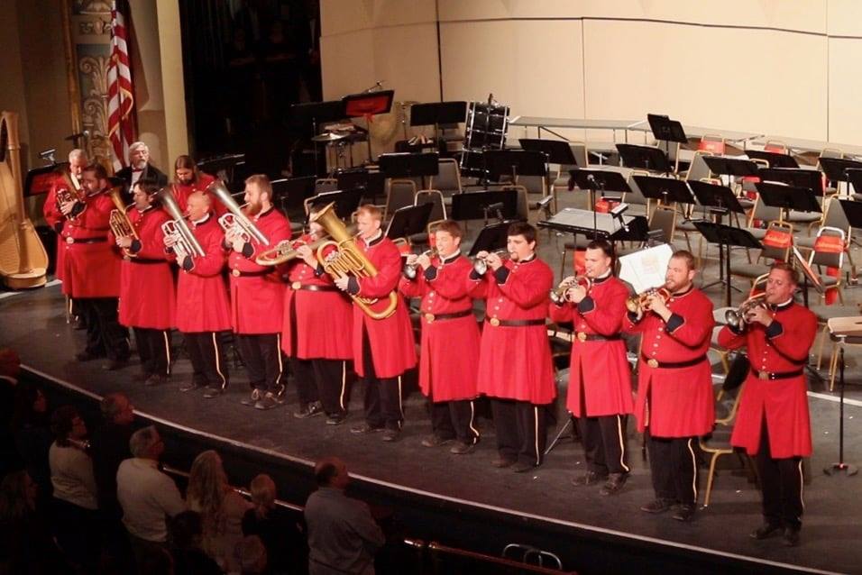 An image of musicians dressed in red military like uniforms.