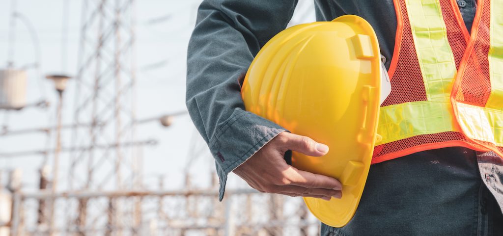 A worker holds a hard hat on a construction site