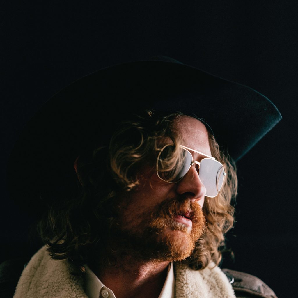 The album cover of "Honey Harper and the Ifinite Sky," featuring Will Fussell in a cowboy hat against a black backdrop.