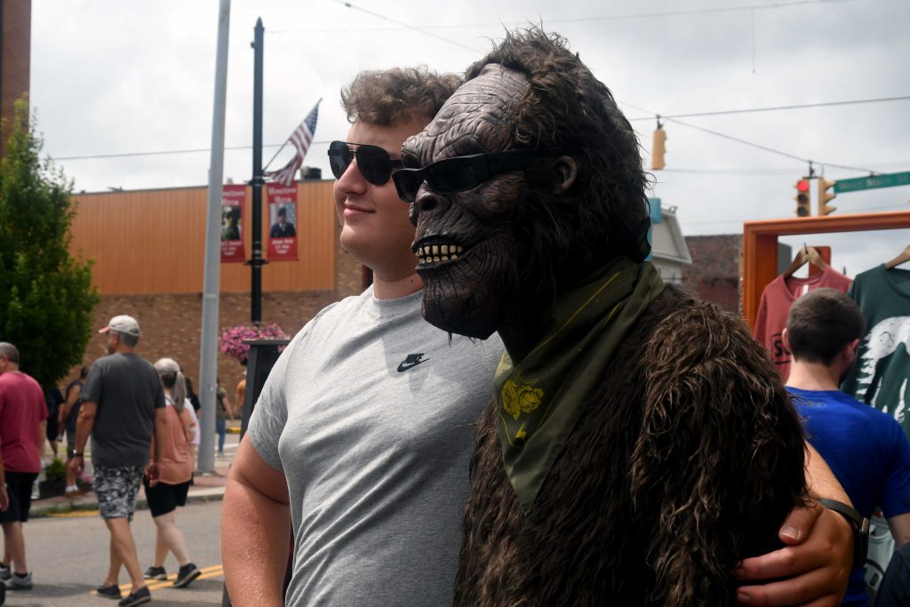 A teenager stands next a statue of Bigfoot.
