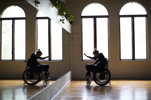 dancer in wheelchair reaching out to mirror