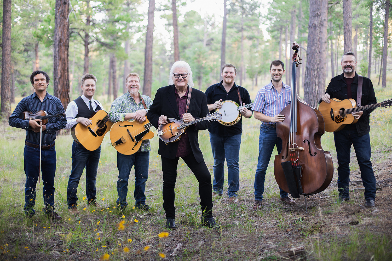 A promotional image for Ricky Skaggs and the Kentucky Thunder. The band is posing in a forest with their instruments.