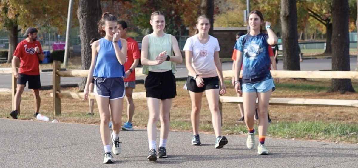 4 members of the Athens Girls Cross Country team walk back to the team after their run