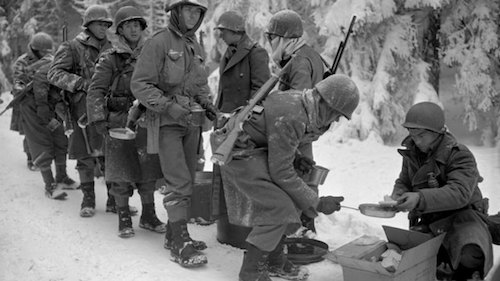 WWII soldiers in the snow lined up for hot food.