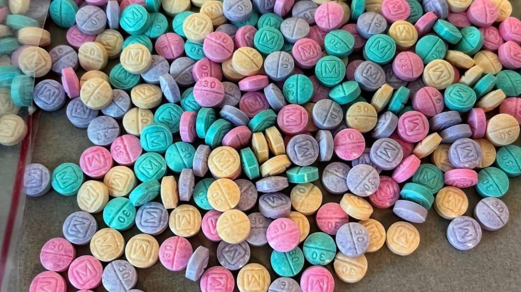  brightly colored rainbow fentanyl pills laid out on a table by DEA and law enforcement partners