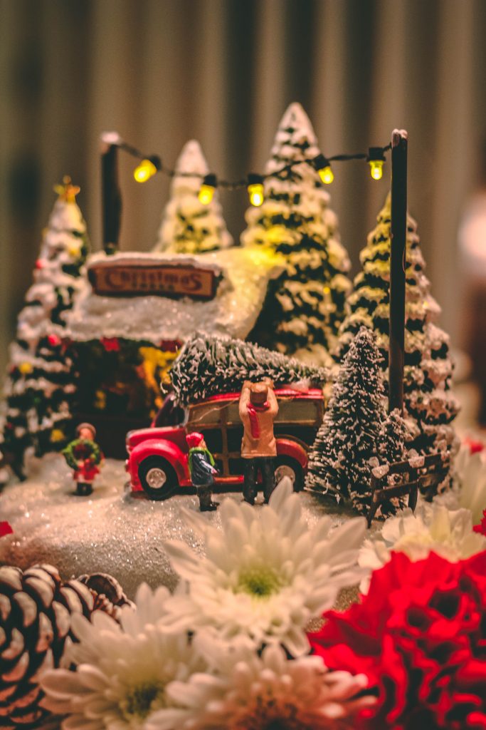 An image of a small Christmas village scaled down with a red truck and snow on tjhe ground
