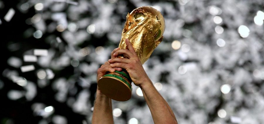 A person holds up the World Cup Trophy as confetti falls