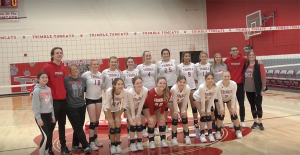 The Lady Tomcats volleyball team posed in front of the volleyball net for a photo. 