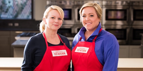 two women chef;s with red aprons faceing camera