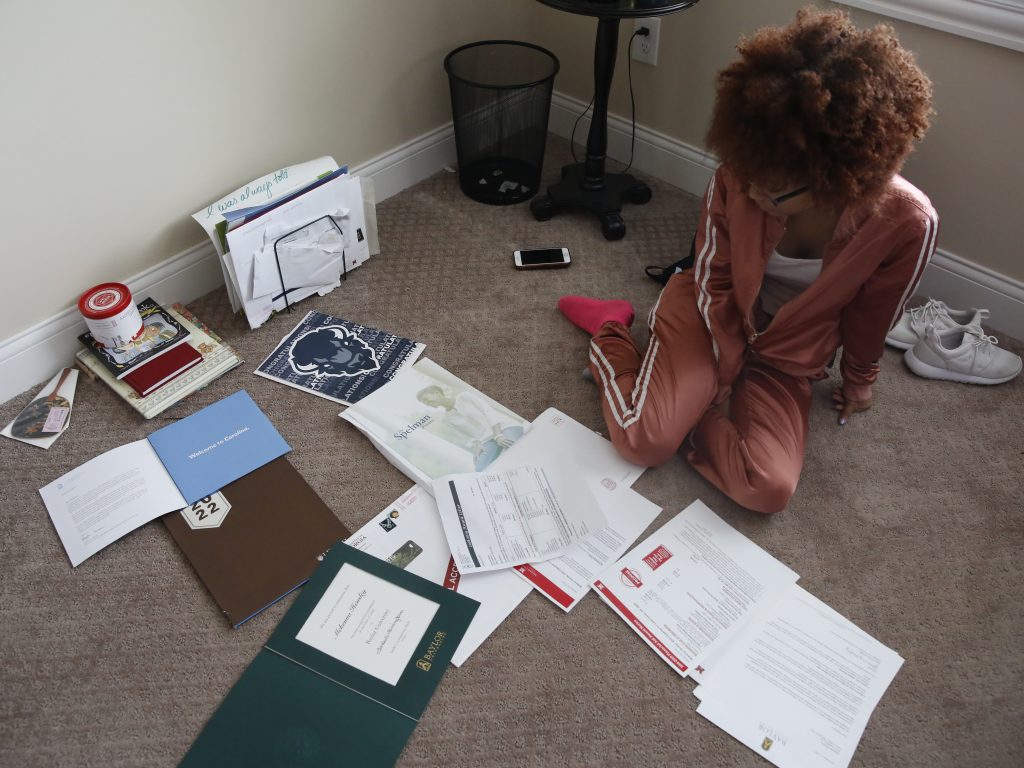 McKenna Hensley sits on the floor of her room as financial aid letters are sprawled out across the floor