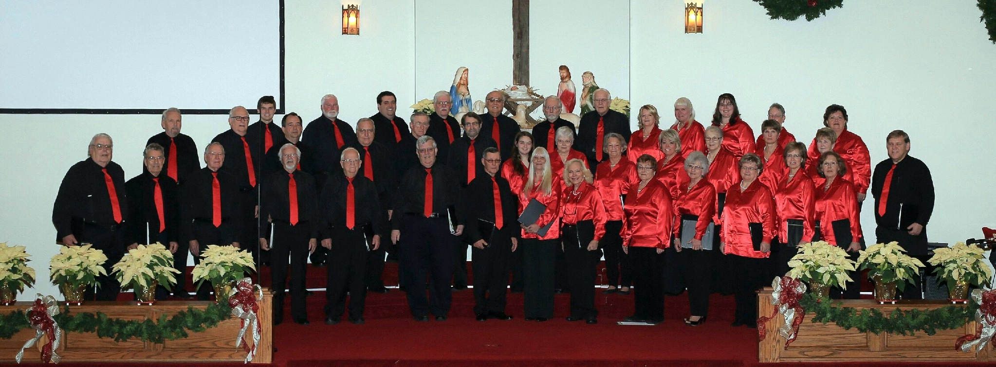A picture of the D.M. Davis Voice Choirs. They are lined up on rafters in robes that are either red or black.