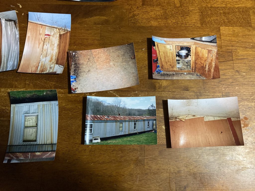 Photos on a wooden table depict a badly run down trailer.