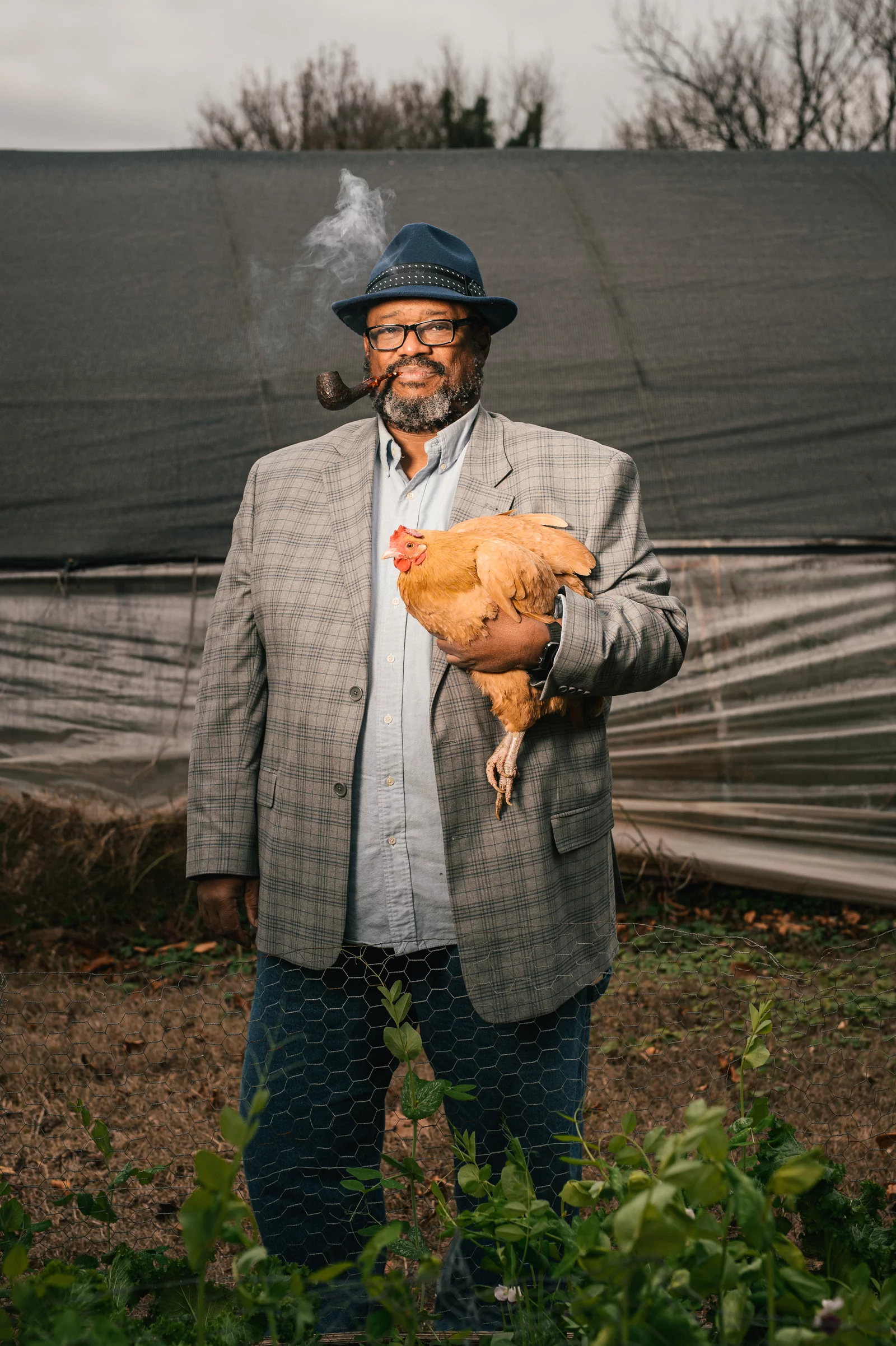 A man stands holding a hen.