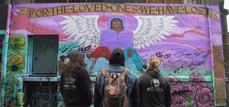 Three men take in the mural they've created of friends who have overdosed.