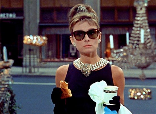A still from the film "Breakfast at Tiffany's" featuring Audrey Hepburn with glasses.