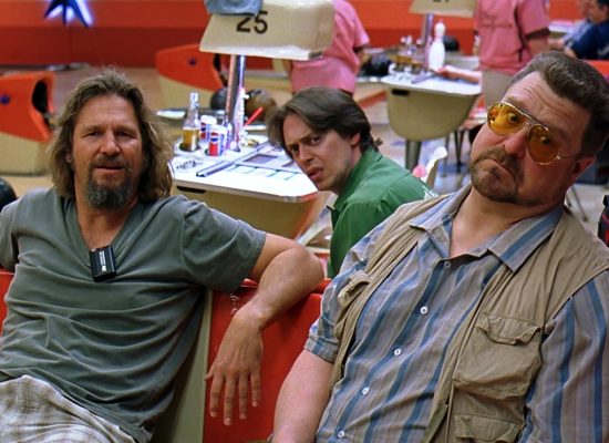 A still from the film "The Big Lebowski" with three men sitting in a bowling alley.
