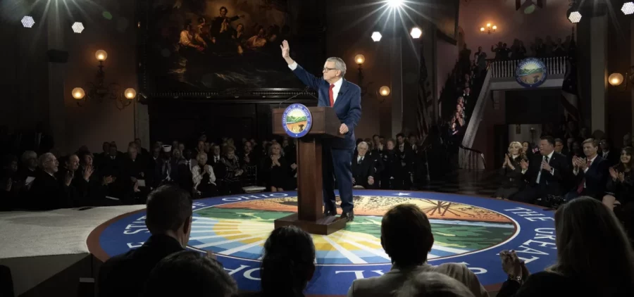 Gov. Mike DeWine waves to the crowd while he stand on a stage that is the Ohio seal during his second inauguration ceremony