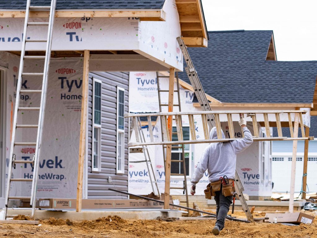 A man carries a ladder through new home construction in Trappe, Maryland.