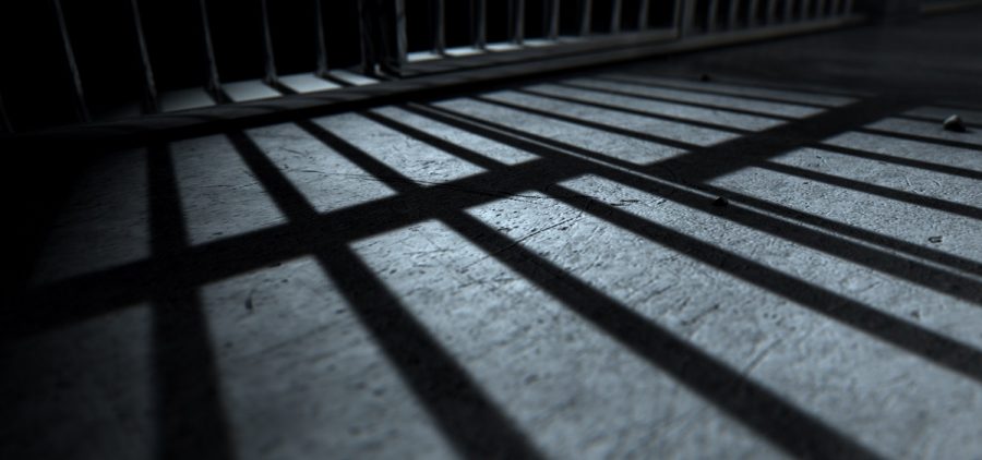 The bars of a prison cell cast a shadow on the ground