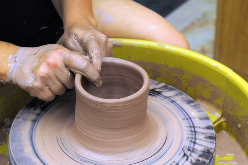 An image of hands working with wet pottery on a wheel.
