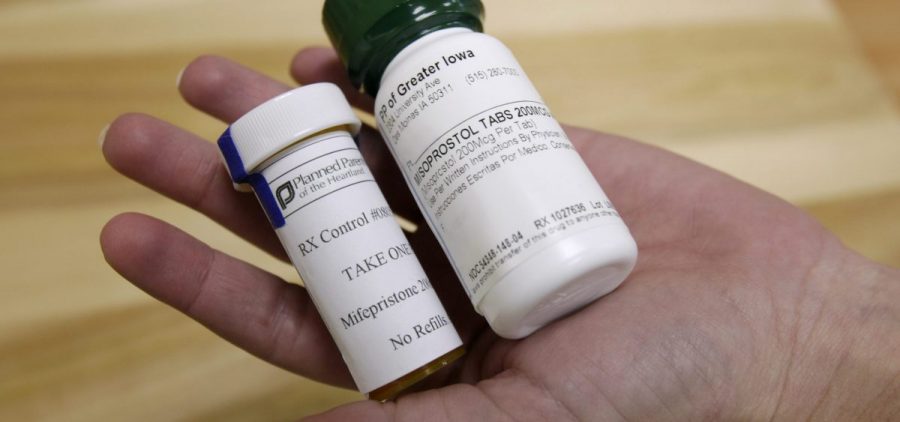 A person holds two bottles of the abortion pill mifepristone in their hand.