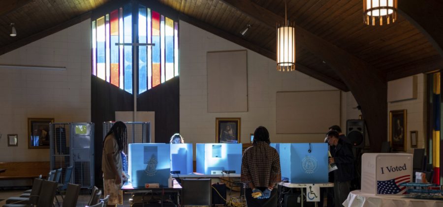 Voters mark their ballots for the midterm election Nov. 8, 2022, at Lawrenceville Road United Methodist Church with stained glass and a cross illuminated in the background