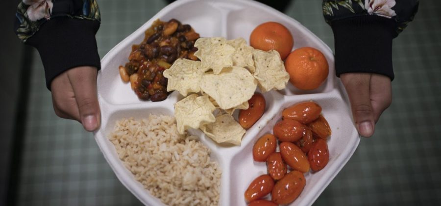 A seventh grader carries her plate of three-bean chili, rice, mandarins and cherry tomatoes and baked chips during her lunch break at a local public school, on Feb. 10 in the Brooklyn borough of New York.