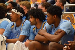 Fifth year guard Sincere Carry sits on the bench between his teammates 