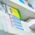 The hand of a pharmacist pulls a medication down from a shelf