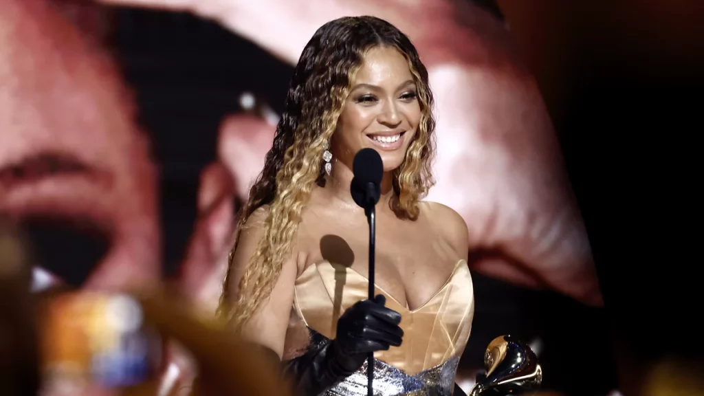 Beyoncé accepts best dance/electronic music album for RENAISSANCE during the 65th Grammy Awards in Los Angeles Sunday. She is in front of a microphone smiling.