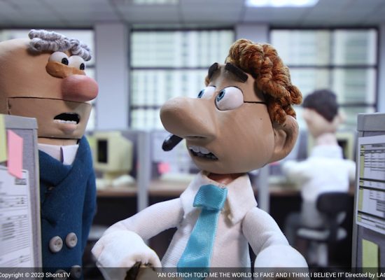 An image from an animated film. The image shows two people in an office, one is sitting down and the other is standing up.