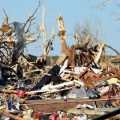 A man sits among the wreckage caused by a series of powerful storms and at least one tornado on March 25, 2023 in Rolling Fork, Mississippi.