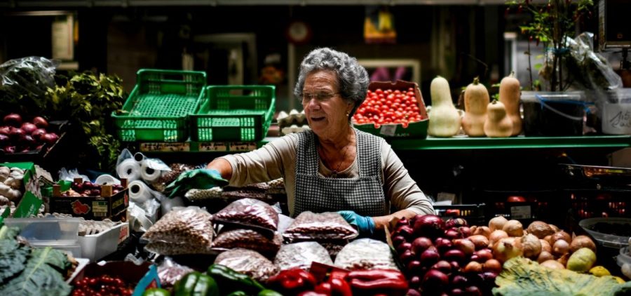 A fruit seller at Dom Pedro market in Coimbra, central Portugal, reaches with gloves on toward some of her produce.