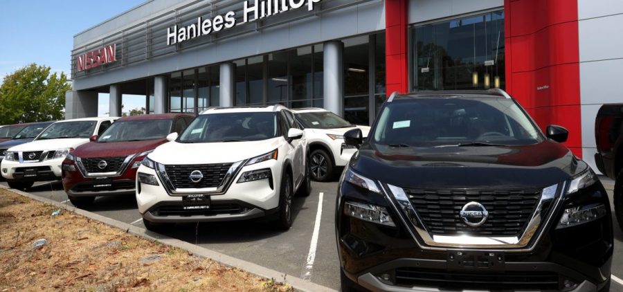 New Nissan cars parked outside a dealership.