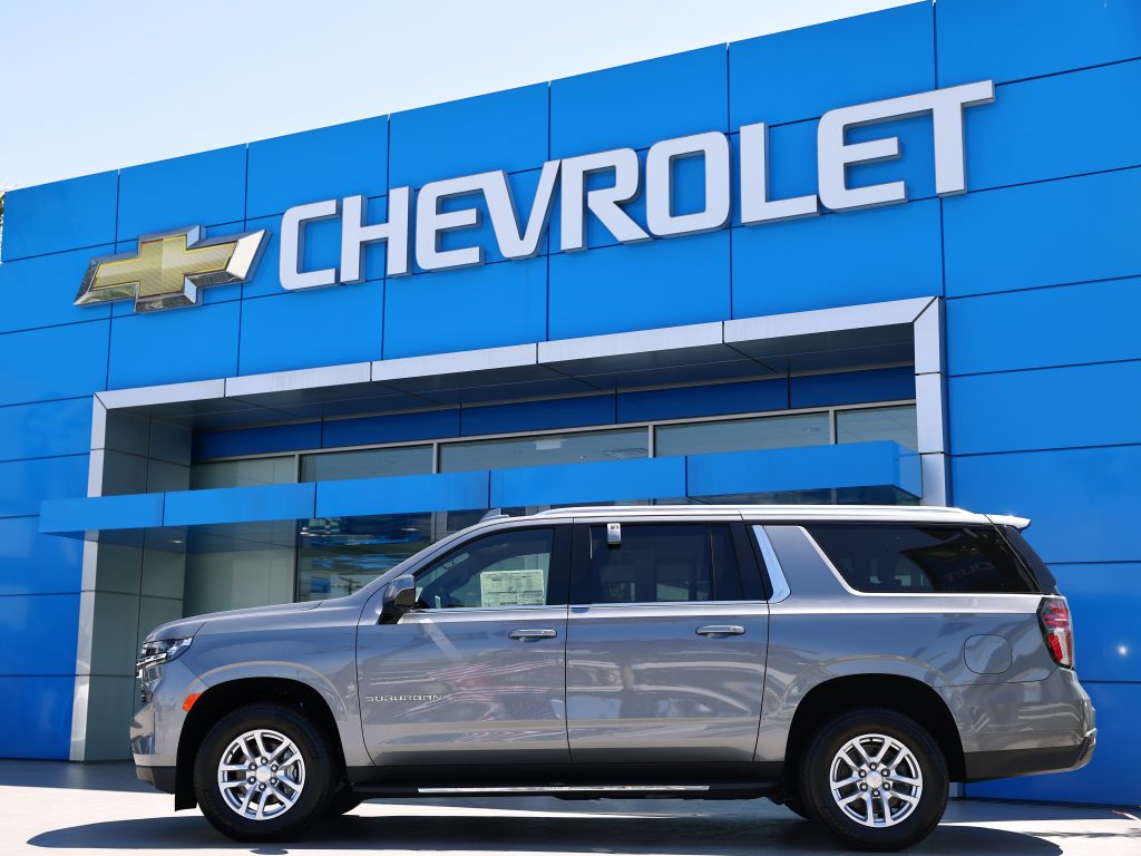 A Chevrolet Suburban parked outside a Chevy dealership.