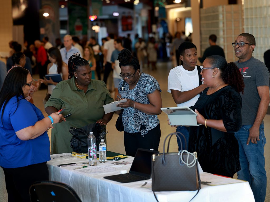 Job seekers fill out forms at the Jamaican Restaurant booth at the Mega South Florida Job Fair held in the FLA Live arena