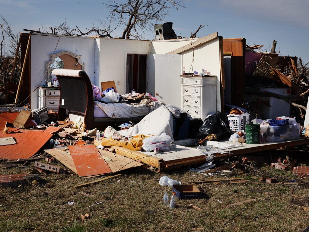 This picture shows one wall of a house still standing after a tornado. It shows the inside of a bedroom.