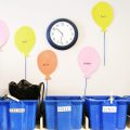 A section of a child care room has tubs with names on them for stuff. There are paper balloons on the wall with children's names.