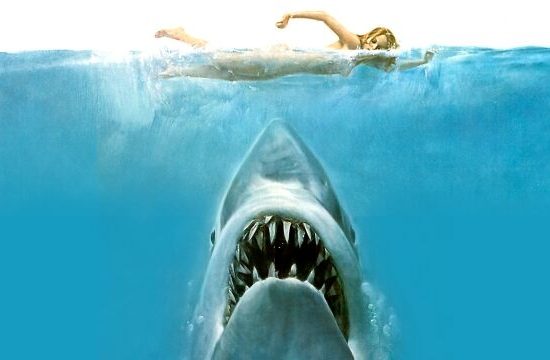 A shot from the film "Jaws" depicting a person swimming above an enormous shark.